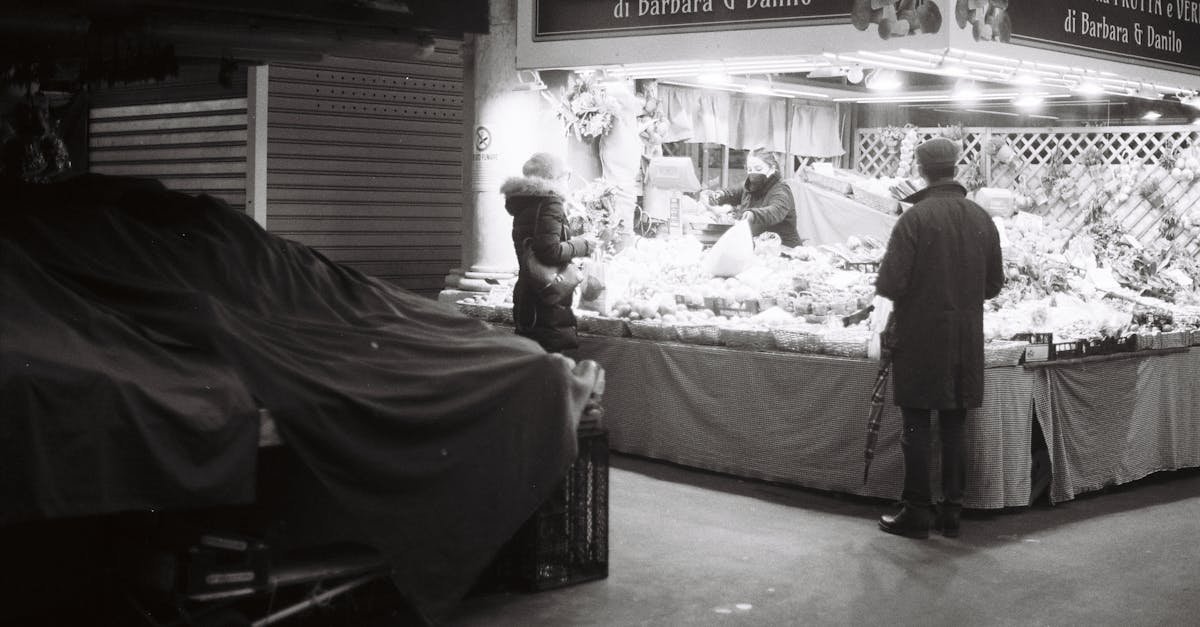 Monochrome street scene of people at a market at night.
