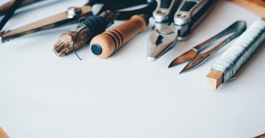 A selection of artisan tools and handmade crafts displayed on a white desk, perfect for creative projects.