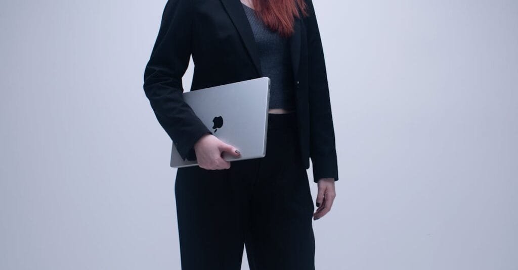Businesswoman in black suit holding a laptop in an office setting.