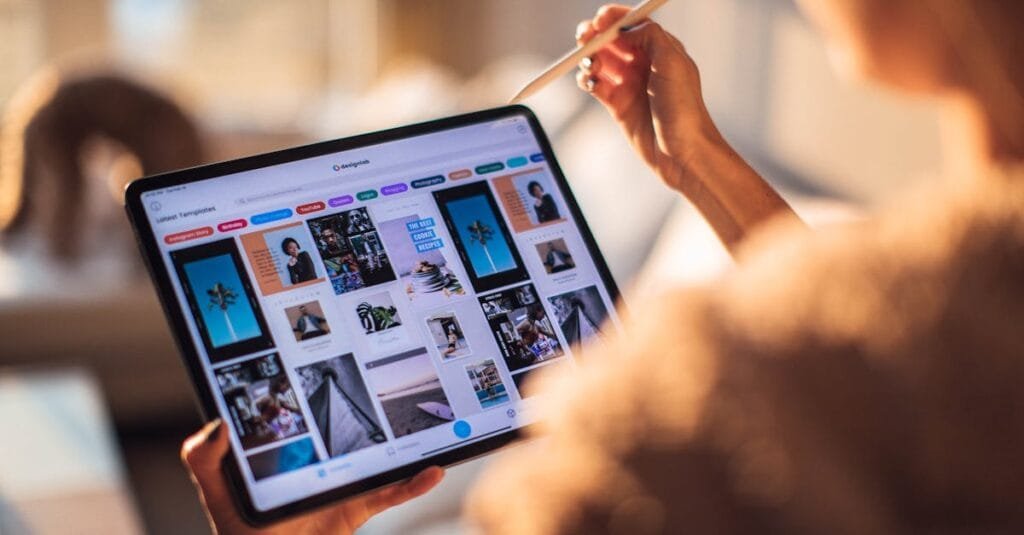 A person uses a digital tablet with a stylus indoors in a warm, cozy setting.