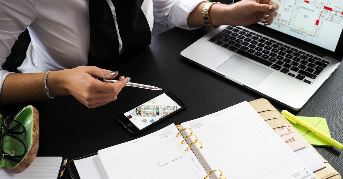 A business professional working on real estate project plans using multiple devices in an office setting.