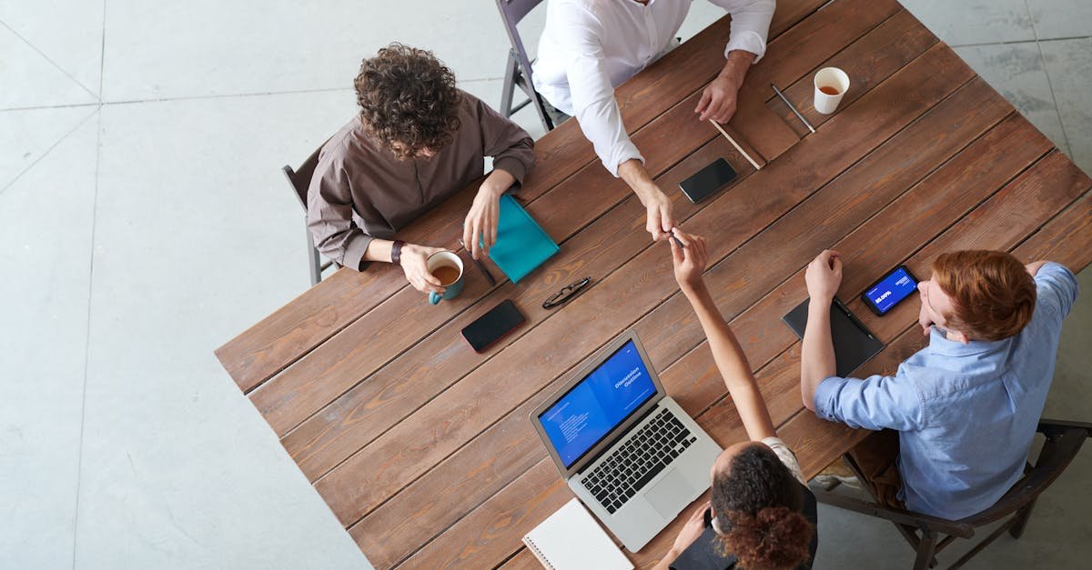 High angle view of a collaborative team meeting in an office setting with laptops and coffee.