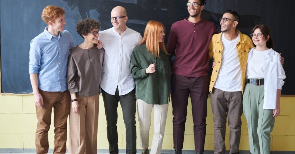 A multicultural group of six adults standing happily together in a casual setting.