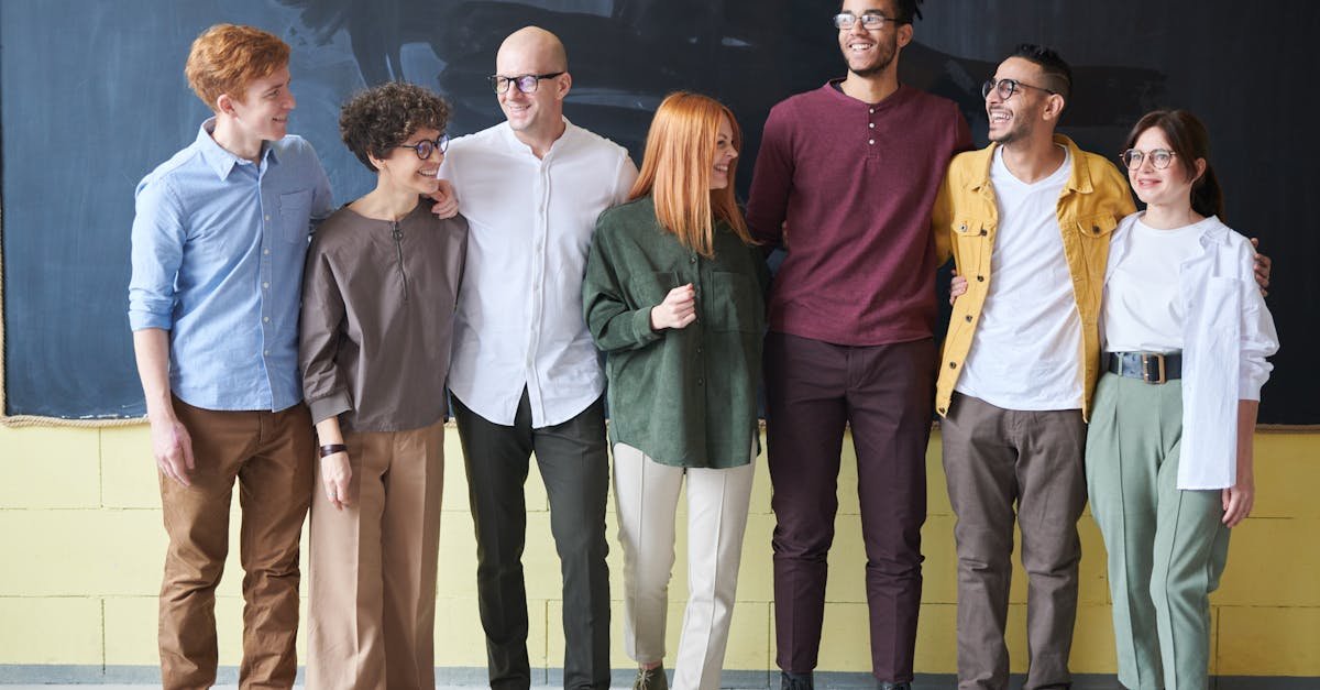 A multicultural group of six adults standing happily together in a casual setting.