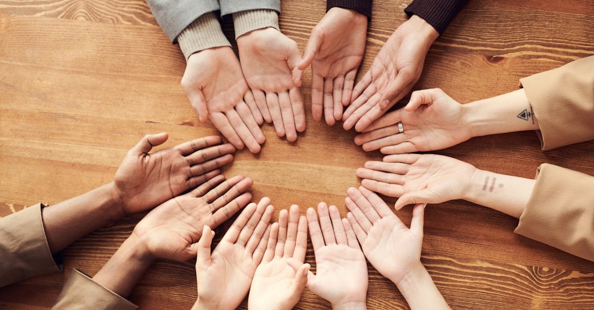 Top view of diverse hands forming a circle on a wooden table, symbolizing unity and diversity.