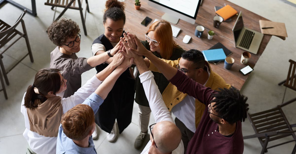 A diverse group of colleagues giving a high five during a corporate meeting indoors.