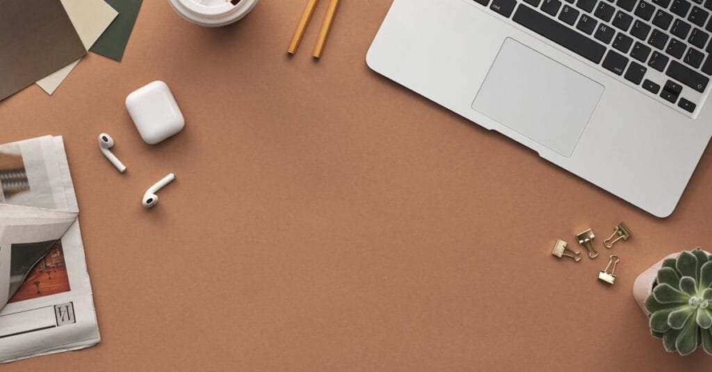 Flat lay of a modern workspace with a laptop, AirPods, and coffee for productivity.