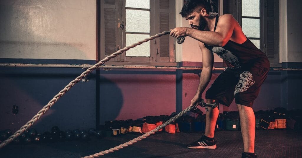 Man performing a challenging Crossfit rope exercise in an indoor gym setting.