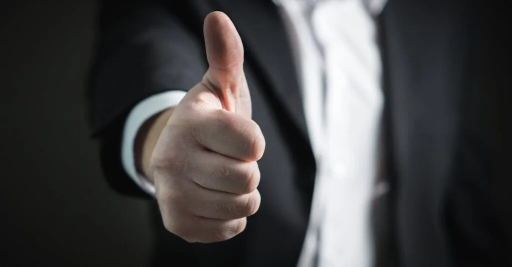 A close-up of a man's thumbs up gesture, symbolizing success and agreement.