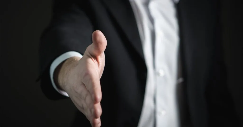 Close-up of a businessman extending hand for a handshake, symbolizing agreement and partnership.