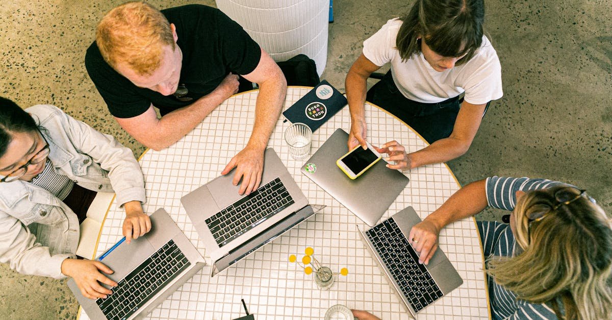 Top view of team collaborating in a modern office around laptops, discussing ideas.