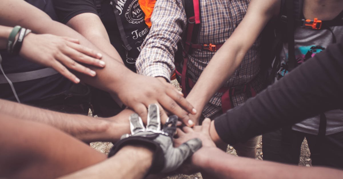 A group of diverse individuals join hands for teamwork in West Java, Indonesia.