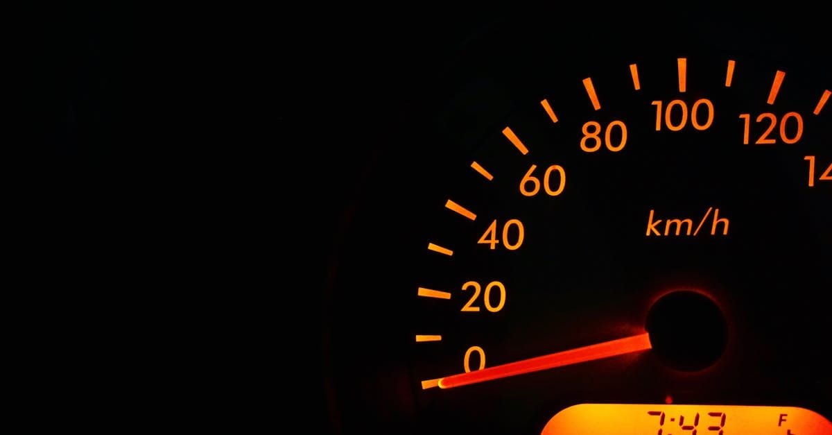 Night view of a car speedometer illuminated in orange, showing kilometers per hour.