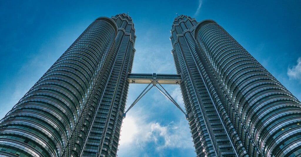 A vibrant view of the iconic Petronas Towers against a clear blue sky in Kuala Lumpur, Malaysia.