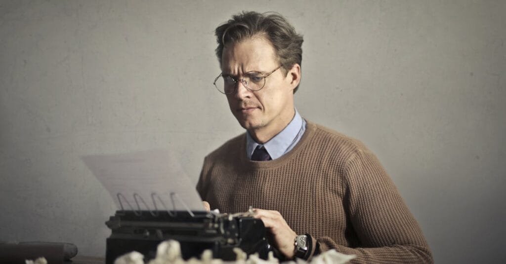A thoughtful writer using a typewriter surrounded by crumpled paper, embodying vintage creativity.