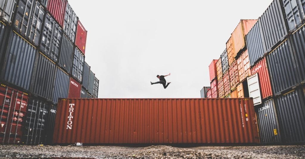 A person leaps dramatically above stacked shipping containers, showcasing freedom and industrial energy.