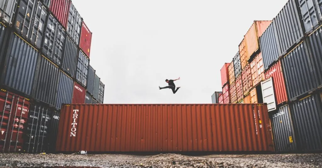 A person leaps dramatically above stacked shipping containers, showcasing freedom and industrial energy.
