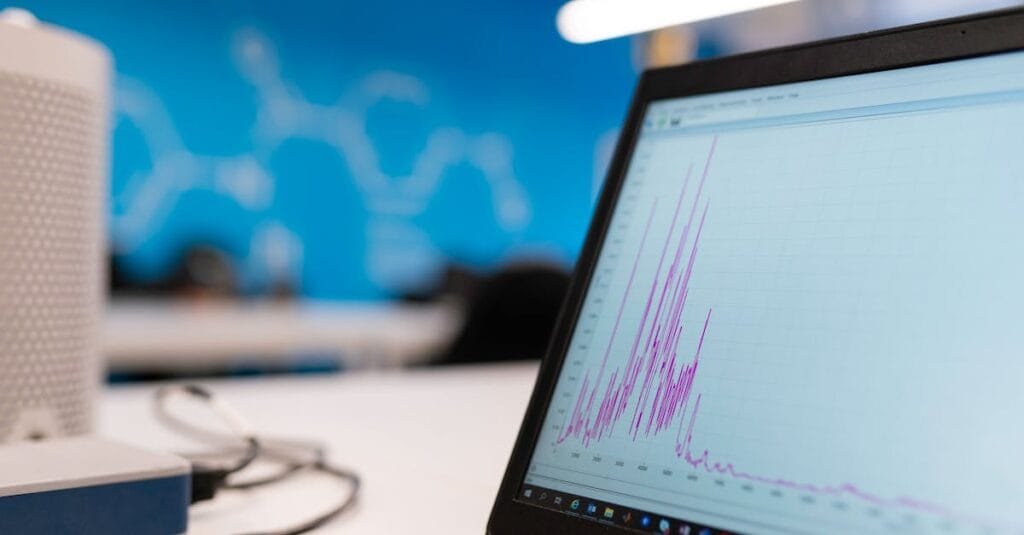 Laptop displaying data analytics graph in a modern office setting, symbolizing growth and technology.