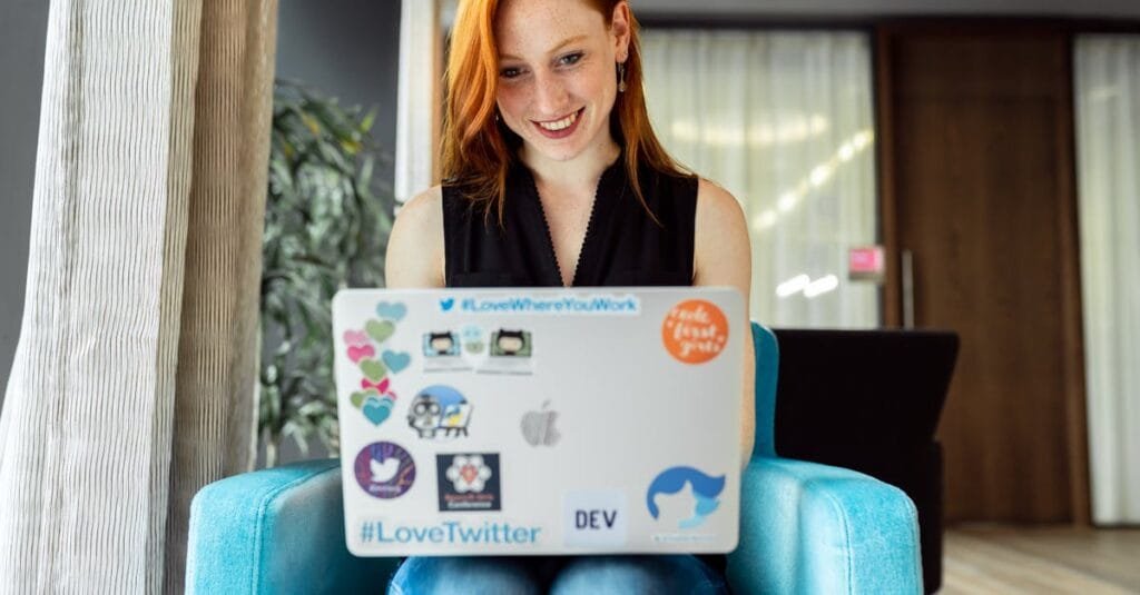 Smiling woman engaged in remote work on a laptop at home office setting.