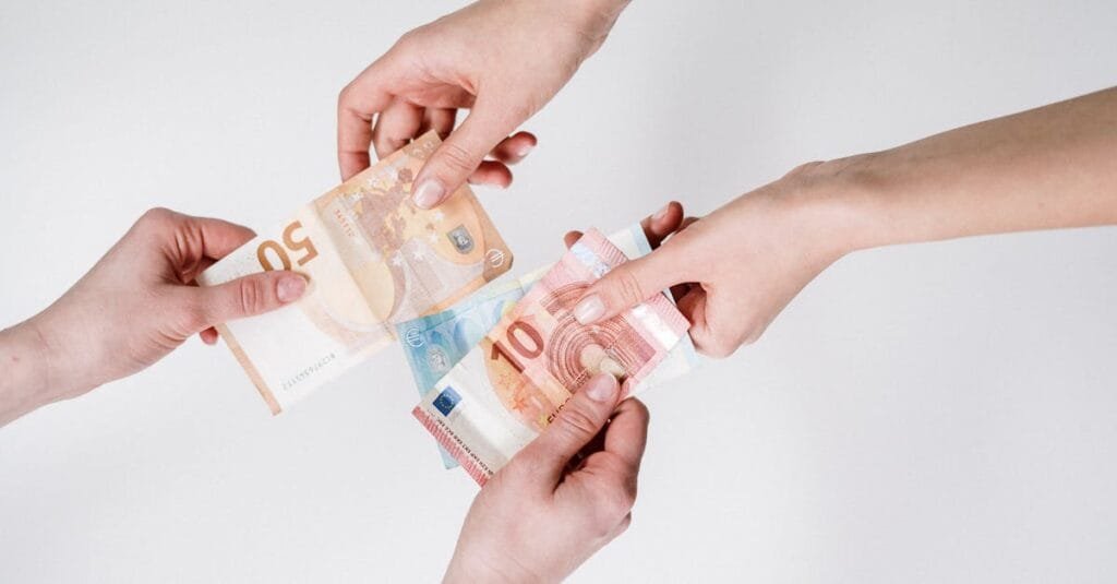 Two pairs of hands exchanging Euro banknotes, symbolizing finance and transaction.