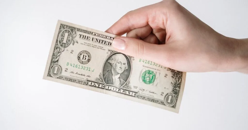 Close-up of a Caucasian hand holding a US one dollar bill against a white background.
