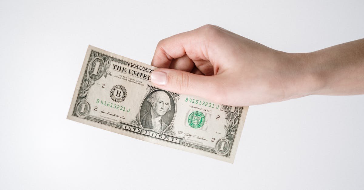 Close-up of a hand holding a one US dollar bill against a white background. Ideal for finance-related themes.