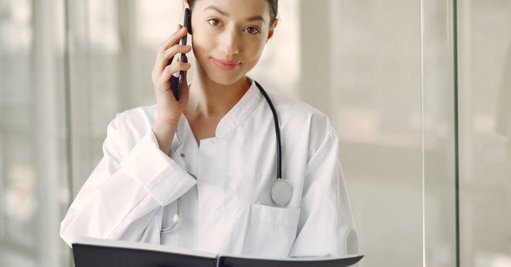 Professional female doctor in white coat talking on phone in medical clinic.