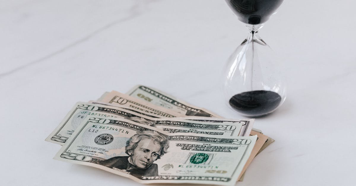 Close-up of US dollar bills with an hourglass, symbolizing time and money.