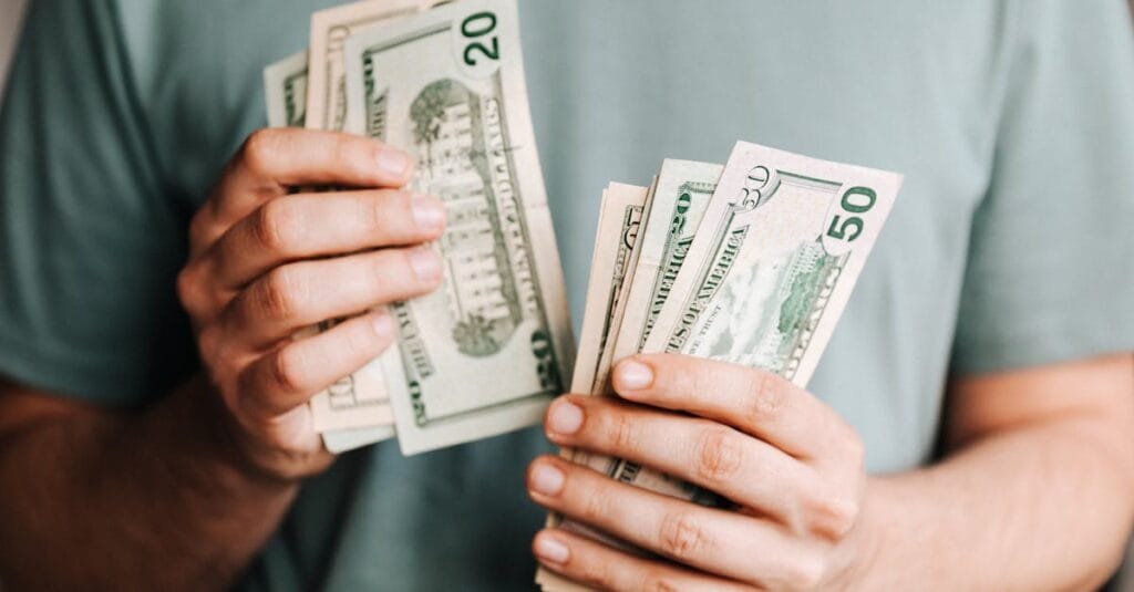 Close-up of a person counting US dollar bills indoors. Financial concept.