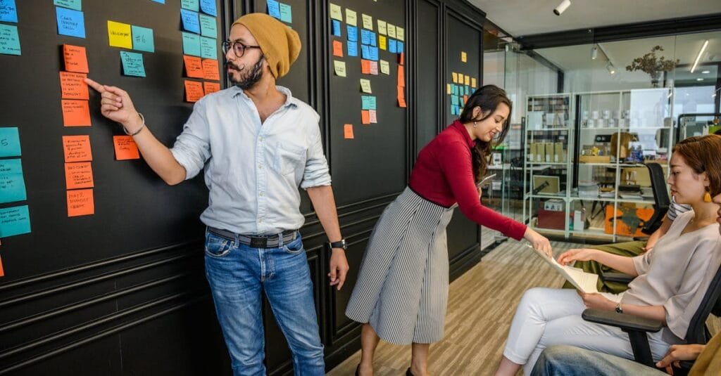 Team members collaborating in a modern office with sticky notes on a wall, focusing on brainstorming and strategy.