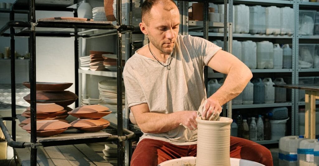 A male artisan focuses on crafting a clay pot using traditional pottery techniques.