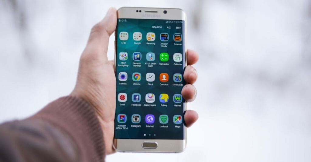 Close-up of a hand holding a Samsung smartphone displaying various app icons, emphasizing technology and connectivity.