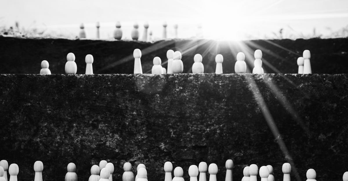 Black and white heap of wooden figurines placed on stairs illustrating social mobility and hierarchy on street with bright sunlight