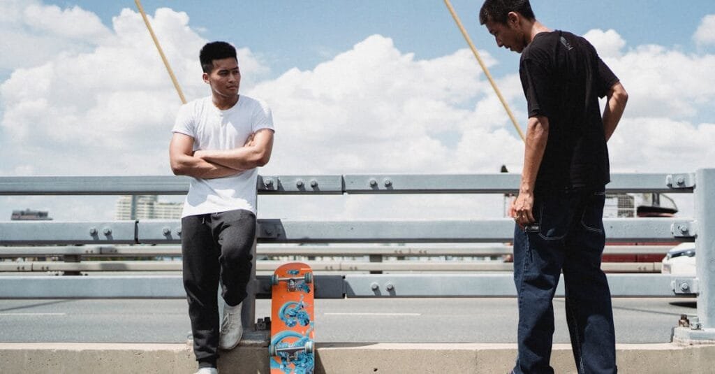 Two young men enjoying a sunny day skateboarding on an urban bridge.