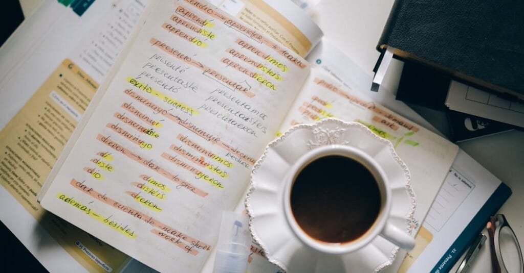 A cup of coffee on handwritten Spanish notes for language learning inspiration.