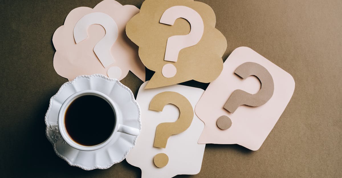 Creative concept with coffee cup and paper question marks on a table.