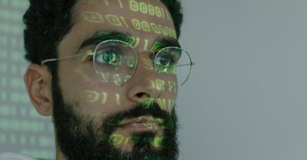 A bearded man with digital binary code projected on his face, symbolizing cybersecurity and technology.