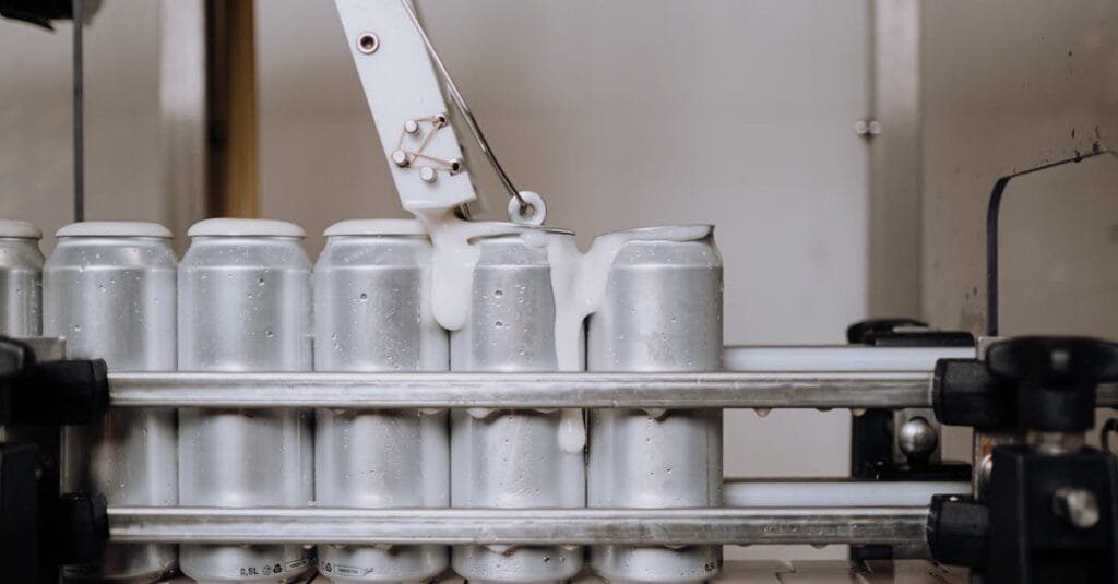 Close-up of aluminum cans being filled in an automated brewery assembly line.