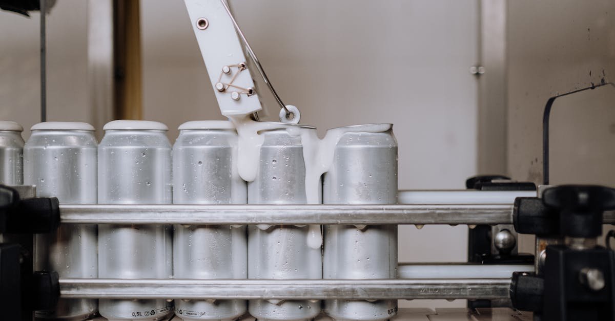 Close-up of aluminum cans being filled in an automated brewery assembly line.