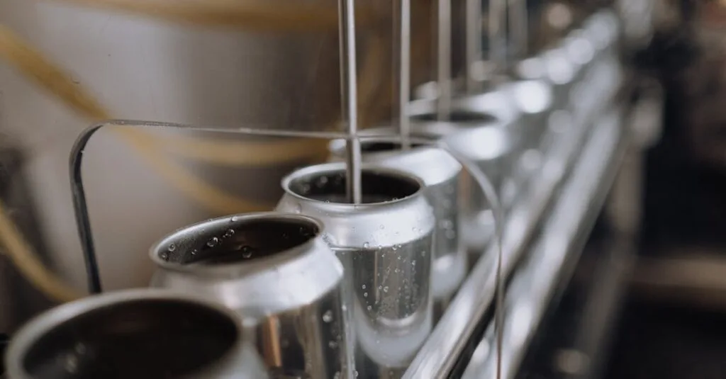 Detailed view of an industrial canning process with aluminum cans on an automatic assembly line.