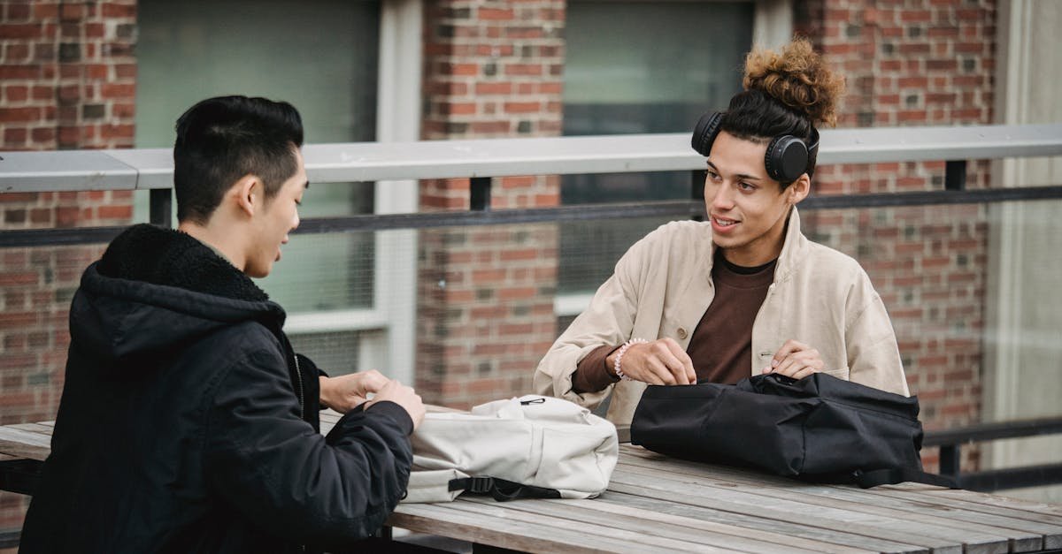 Two young men having a casual conversation at an outdoor table, enjoying free time.