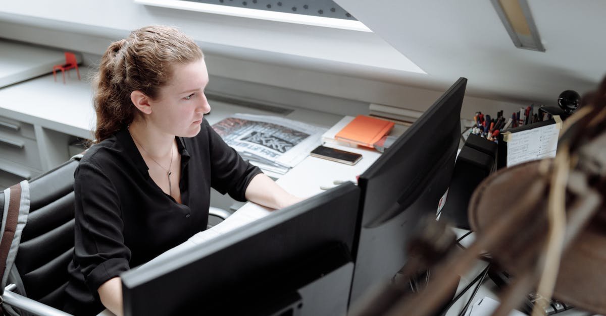 Woman working diligently at a computer desk in a bright, modern office setting, showcasing productivity and focus.