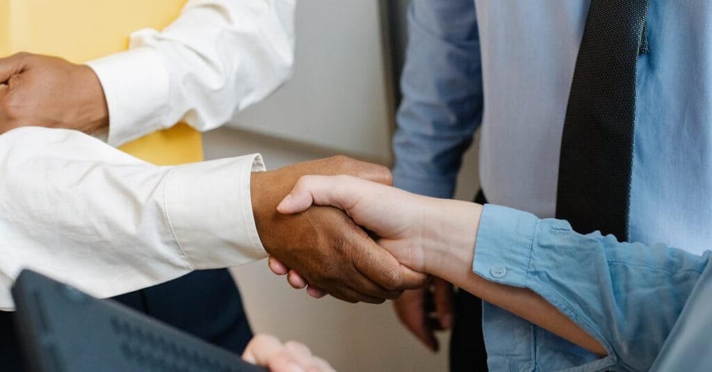Crop anonymous diverse entrepreneurs shaking hands after meeting and negotiating about new project