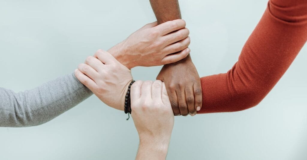 Close-up of diverse hands holding each other in a symbol of unity and togetherness.