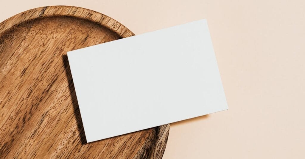 Minimalist blank card on a wooden plate placed against a soft pastel background, perfect for mockups.