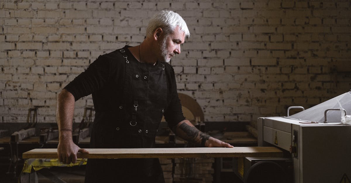 A middle-aged craftsman focuses on woodworking with a lathe in a workshop.