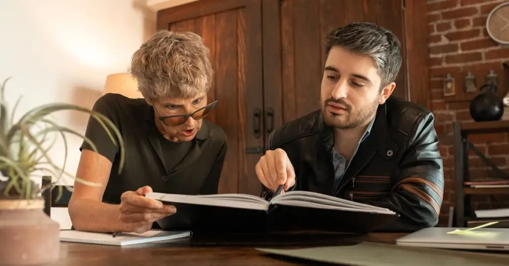An elderly woman and a man study together in a cozy indoor environment.