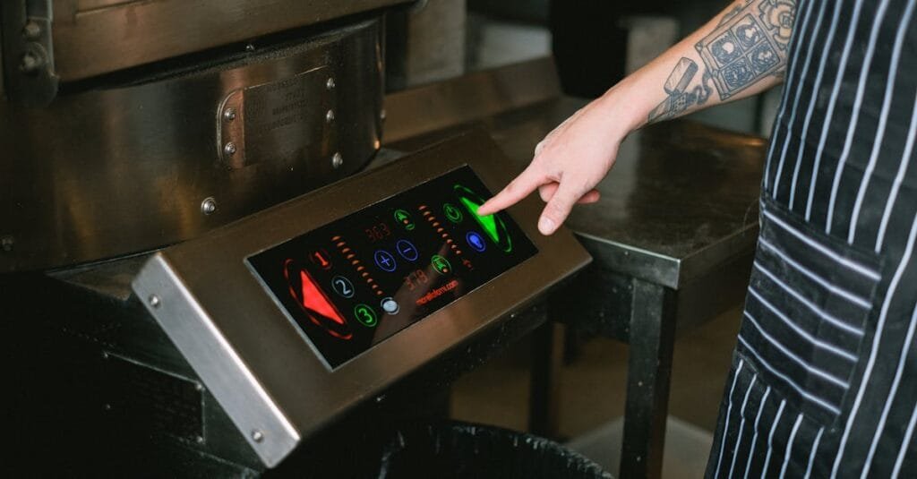 Close-up of a chef using a touchscreen control panel in a modern kitchen.