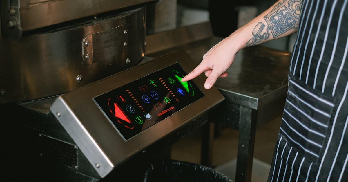 Close-up of a chef using a touchscreen control panel in a modern kitchen.