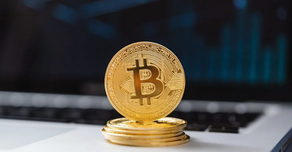 A shiny gold Bitcoin coin on laptop keyboard, symbolizing digital currency and blockchain technology.